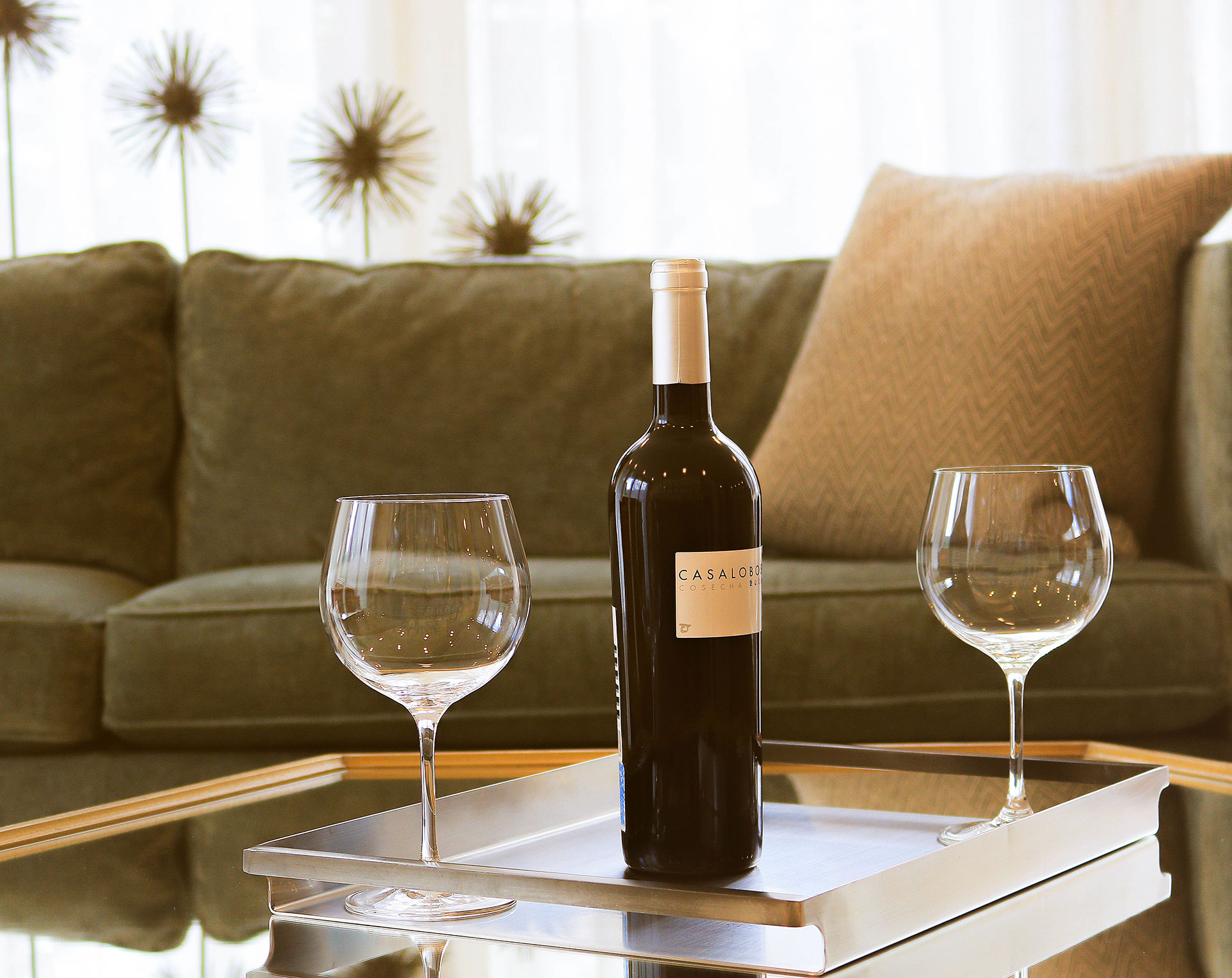 A professional photo of a bottle of wine and two wine glasses on a table.