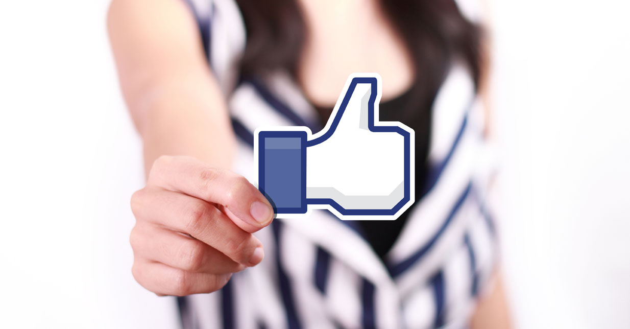 Woman holding the Facebook "like" icon