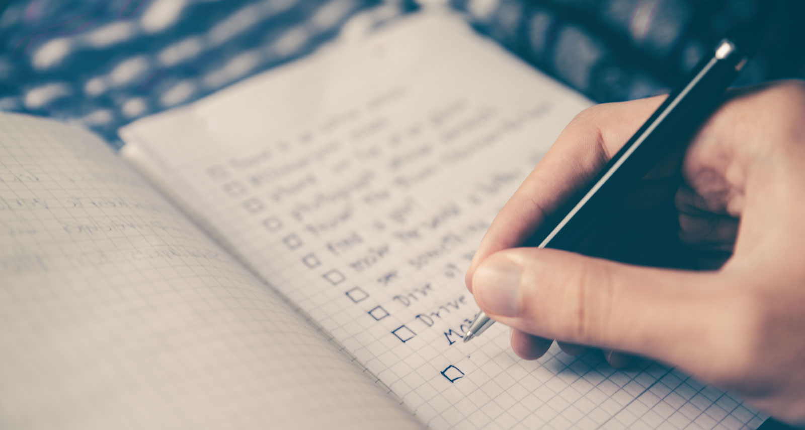 A person writing down a checklist in a notebook.