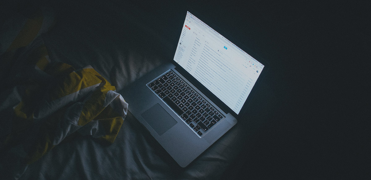 A dimly lit laptop displaying a full email inbox